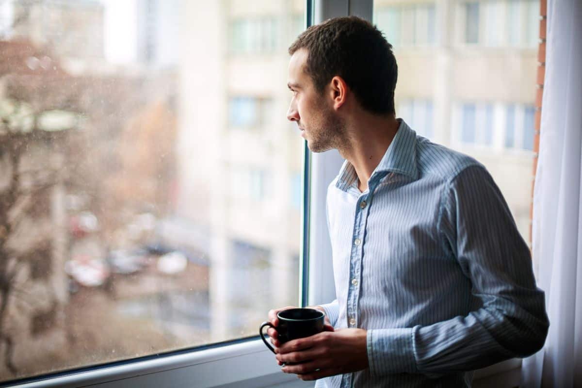 Man looking out of a window contemplating life