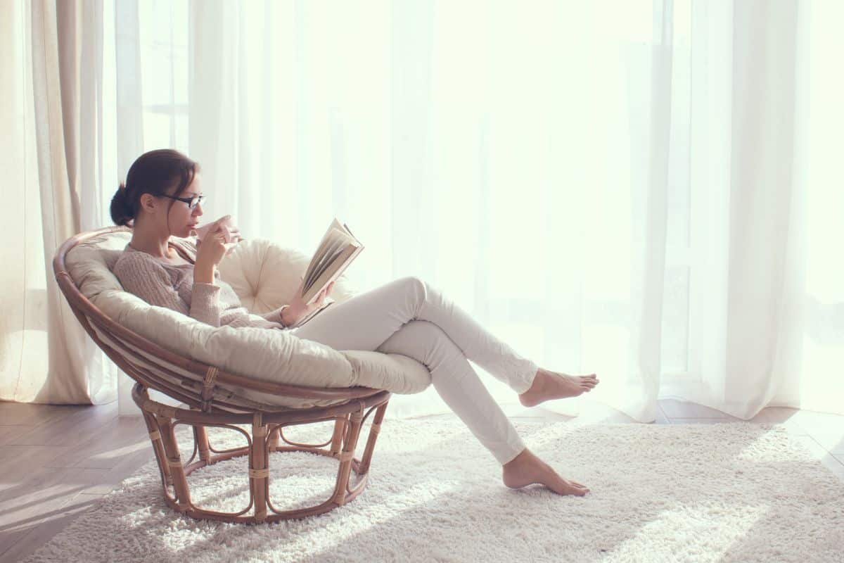 woman relaxing while reading a book and drinking a tea