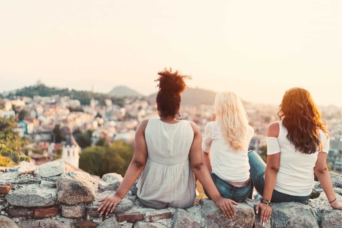 three friends sitting on a hill